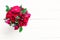 Home roses in a glass vase on a white wooden table flat lay. With copy space
