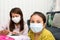 Home schooling concept image with mother and daughter studying while wearing face masks because of current corona virus threat