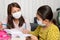 Home schooling concept image with mother and daughter studying while wearing face masks because of current corona virus threat