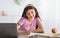 Home schooling. Joyful Indian teenage girl in headphones taking notes during online class on laptop indoors