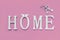 Home, wooden text with heart shape decor on pink background. Concept of building houses, choosing your own house, mortgage, buying