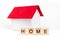 Home- word composed fromwooden blocks letters on red background, layout of a house with a red roof. copy space for ad
