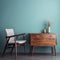 Home workplace with wooden drawer writing desk and grey fabric chair near turquoise wall with copy space