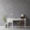 Home workspace with white drawer writing desk and grey chair against of window near grey stucco wall