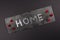 Home written with Gemstones on a stone background surrounded by red flowers. Home Sweet Home Concept