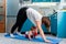 Home yoga. A young Caucasian mother does Adho Mukha Shvanasana while her baby crawls under her on the mat. The concept of sports