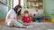 At home a young mom with her son reading a book story sitting down on the floor while the dad in background working from