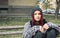 Homeless girl, Young beautiful red hair girl sitting alone outdoors on the wooden bench with hat and shirt feeling anxious and dep