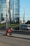 A homeless guy sits on the sidewalk with a cardboard and an inscription: need job. In the background is a business center