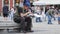 Homeless man with beard eats from plastic plate sitting on the street