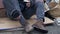 Homeless man sitting by a pile of rubbish holds a paper begging cup in his dirty, trembling hands. Poor man needs help.