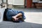 Homeless man sleeps on the street, in the shadow of the building.