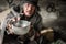 Homeless old man with gray beard and hair sitting holding metal bowl with food beggar