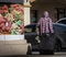 Homeless person pulling suitcase passing a market sign with a photo of various