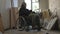 Homeless poor man sitting in a wheelchair in a room of an abandoned building filled with his meager belongings. He is