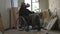 Homeless poor man sitting in a wheelchair in a room of an abandoned building filled with his meager belongings. He