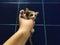 Homeless tiny kitten in the hand in front of blue tile background