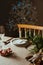 Homely christmas table setting, decorated with pine branches and rustic tablecloth in the living room of home tree lit background