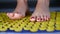 Homemade acupuncture massage with caucasian female legs standing on an acupressure mat. front view of female legs on a