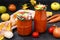 Homemade adzhika with tomatoes, apples and carrots in jars on a dark background