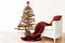 Homemade alternative Christmas tree of rustic raw wood branches decorated with fairy lights and red balls next to an armchair with