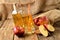 Homemade apple juice with ice, red apples, straw, still life on a wooden table