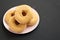 Homemade autumn apple-cinnamon donuts on a pink plate on a black background, side view. Space for text