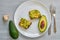 Homemade avocado toasts on the white plate with black salt and garlic ready to eat. Avocado sandwiches on the gray background