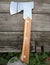 Homemade ax with rivets and wooden handle lies on old planed wooden boards