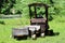 Homemade backyard garden decoration made to resemble small train with single cart surrounded with uncut grass next to paved road