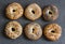 Homemade bagels with a variety of seeds on a gray background, top view.