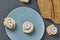 Homemade baked buns in form of rose spangled of powdered sugar on gray round plate near sackcloth lies on dark concrete desk. Conf