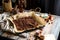 Homemade baked chocolate granola with nuts, oat flakes on baking tray with parchment stands on grey wooden table