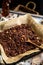 Homemade baked chocolate granola with nuts, oat flakes on baking tray with parchment stands on grey wooden table