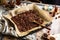 Homemade baked chocolate granola with nuts, oat flakes on baking tray with parchment stands on grey wooden table