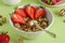 Homemade baked muesli, nuts, fresh strawberries on a green background. Healthy breakfast in a white bowl with natural granola