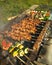 Homemade barbecue on the grill with open fire and smoke. Meat and vegetables with mushrooms and zucchini on wooden sticks.