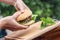 Homemade beef or pork hamburger with vegetable and basil leaf in woman hands in garden, food photography