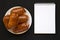 Homemade beef sausage kolache on a white plate, blank notepad on a black surface, top view. Flat lay, overhead, from above,