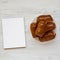 Homemade beef sausage kolache on a white plate, blank notepad on a white wooden surface, top view. Copy space