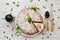 Homemade berry pie on plate, blueberries in mug, wooden spoon with berries, knife and scattered blueberries on wooden background