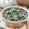 Homemade black bean and ham soup in aluminum bowl on wooden table, top view, square