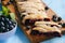 Homemade blueberry puff pastry braid, on blue wooden background.