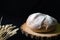 Homemade bread on a wooden saw with ears of wheat on a dark background