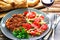 Homemade Breaded German Weiner Schnitzel and fresh vegetable spring salad with tomato, green olives, cabbage and parsley