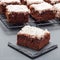 Homemade brownie with coconut flakes, swedish dessert Karleksmums, cut in square servings, on stone plate and cooling rack, square