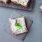 Homemade brownie with coconut flakes, swedish dessert Karleksmums, cut in square servings, on stone plate and cooling rack, top