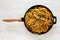 Homemade Bucatini all Amatriciana Pasta in a cast iron pan on a white wooden background, top view. Flat lay, overhead. Close-up