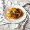 Homemade Bucatini all Amatriciana Pasta in a white plate on cloth, low angle view