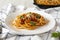 Homemade Bucatini all Amatriciana Pasta in a white plate on a white wooden surface, low angle view. Close-up